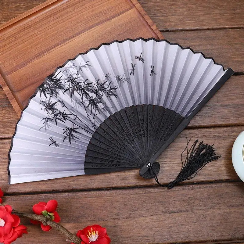 A folding fan made of bamboo and silk with a gray and black pleated design featuring delicate floral silhouettes.