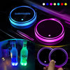 A hand holds a set of customizable LED cup holder lights with various colors illuminating the interior of a car.