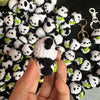 A hand holds a handmade crochet kitten keychain featuring a cute panda and cartoon animal charm.
