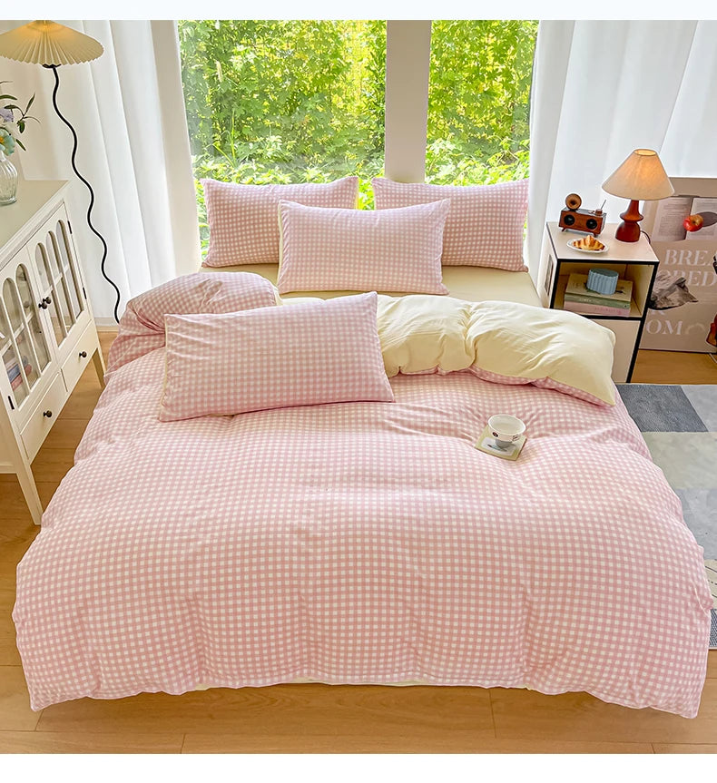 A pink gingham duvet cover set with two pillows is displayed on a bed in a bright, airy room.