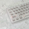 Translucent white PC keycaps for a mechanical keyboard displayed on a white fabric with scattered ice crystals.