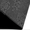 Close-up view of a black doormat with a speckled pattern, shown at an angle.