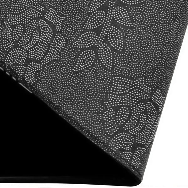Close-up view of a black doormat with a speckled pattern, shown at an angle.