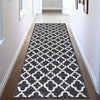 A geometric runner rug featuring a pattern of white and grey diamonds on a dark grey background.