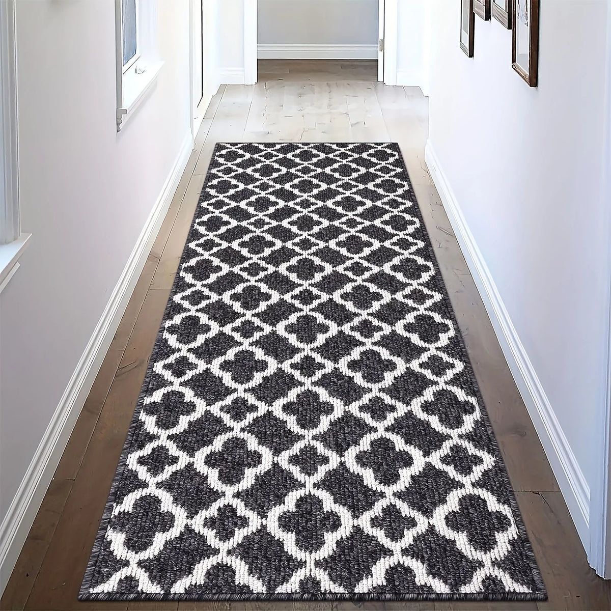 A geometric runner rug featuring a pattern of white and grey diamonds on a dark grey background.