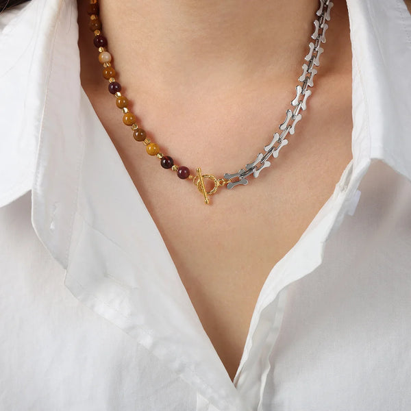 Rapproché d'un collier en acier inoxydable fait main avec des perles ambre et violettes, porté contre une chemise blanche à c