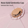 A rose gold umbrella cap resting on pink fabric.