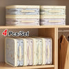 Four sets of foldable bedding storage bags with handles stacked on a wooden shelf.