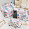 A collection of colorful patchwork quilted makeup bags and a butter-colored book are displayed on a white surface.