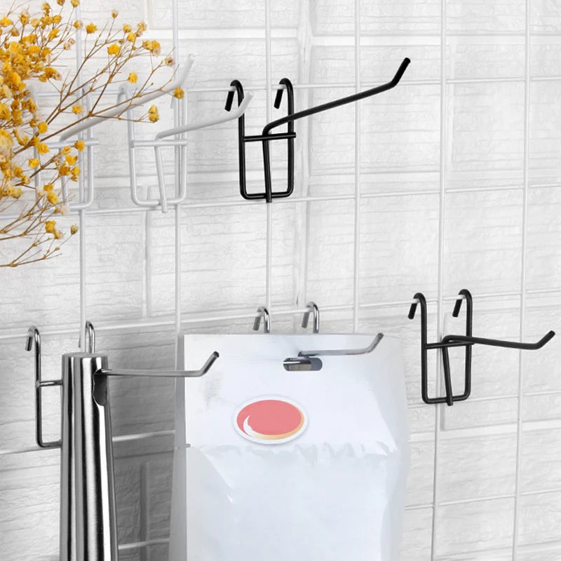 A set of five black heavy duty grid hooks mounted on a white tiled wall above a white toilet.