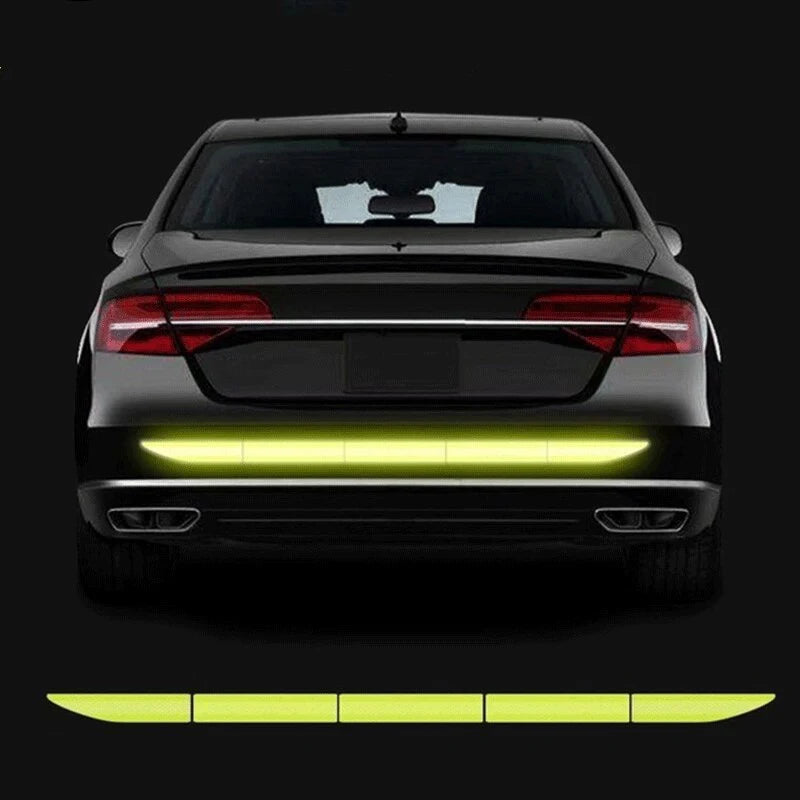 Rear view of a black car with yellow high-visibility reflective safety tape installed on the lower bumper.