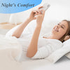 Eine Frau macht Fotos mit einem Smartphone, während sie auf einem weißen Bett mit einem Memory-Foam-Kissen entspannt.