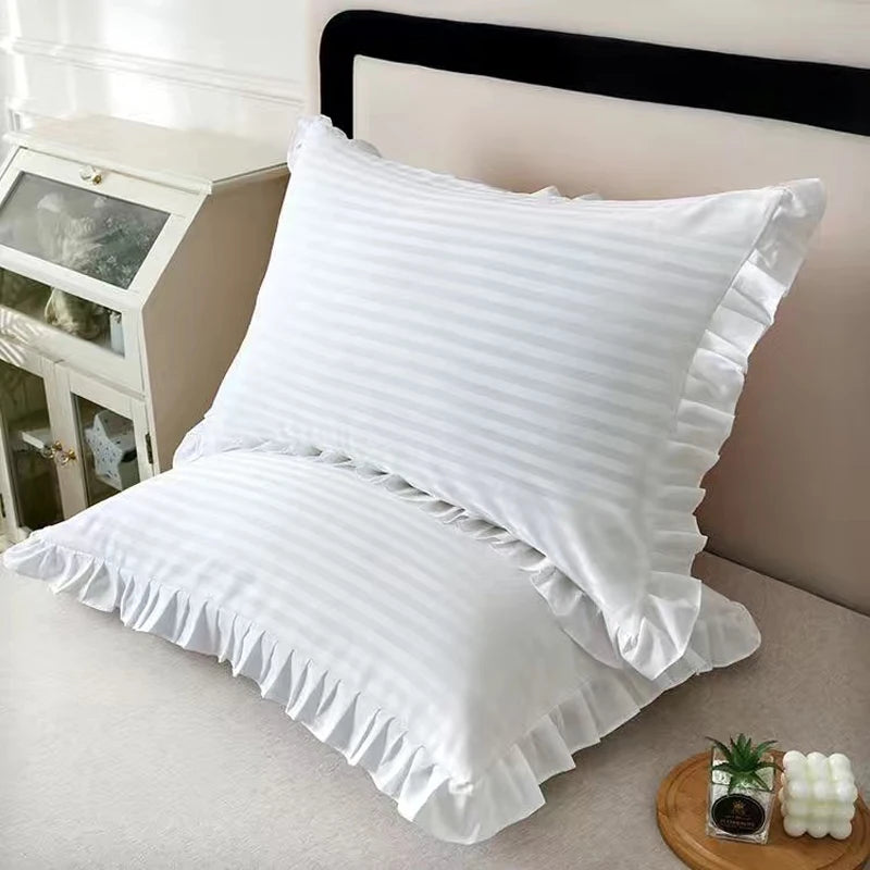 White striped pillow covers with ruffled edges displayed on a bed.