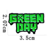 A bright green enamel pin featuring the text GREEN DAY with a cross symbol.