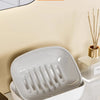 A white double-layered draining soap dish with a non-slip base shown on a countertop.