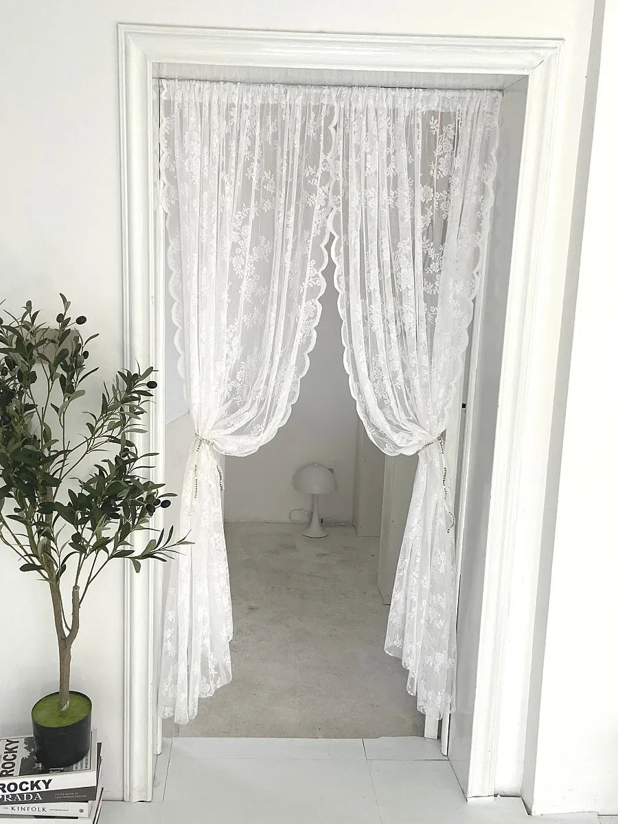 Rideau transparent à broderie florale blanche suspendu dans un cadre de porte blanc.