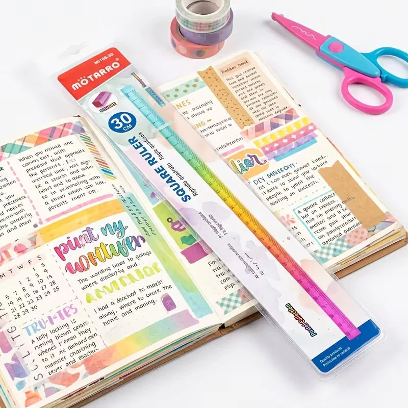 A colorful geometric cube drawing tool with a straight edge and pink scissors is shown on a white surface.