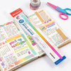 A colorful geometric cube drawing tool with a straight edge and pink scissors is shown on a white surface.