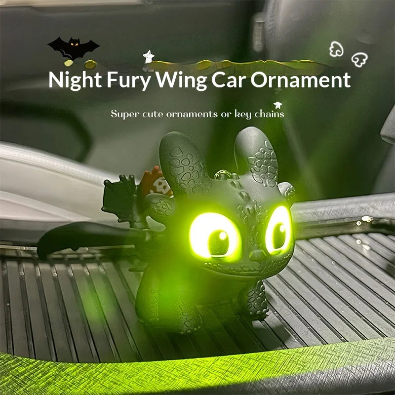 A glowing green Toothless car ornament with movable wings placed on a car interior surface.