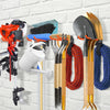 A wall-mounted organizer rack displaying various heavy-duty garden tools including shovels, hoes, and other implements.