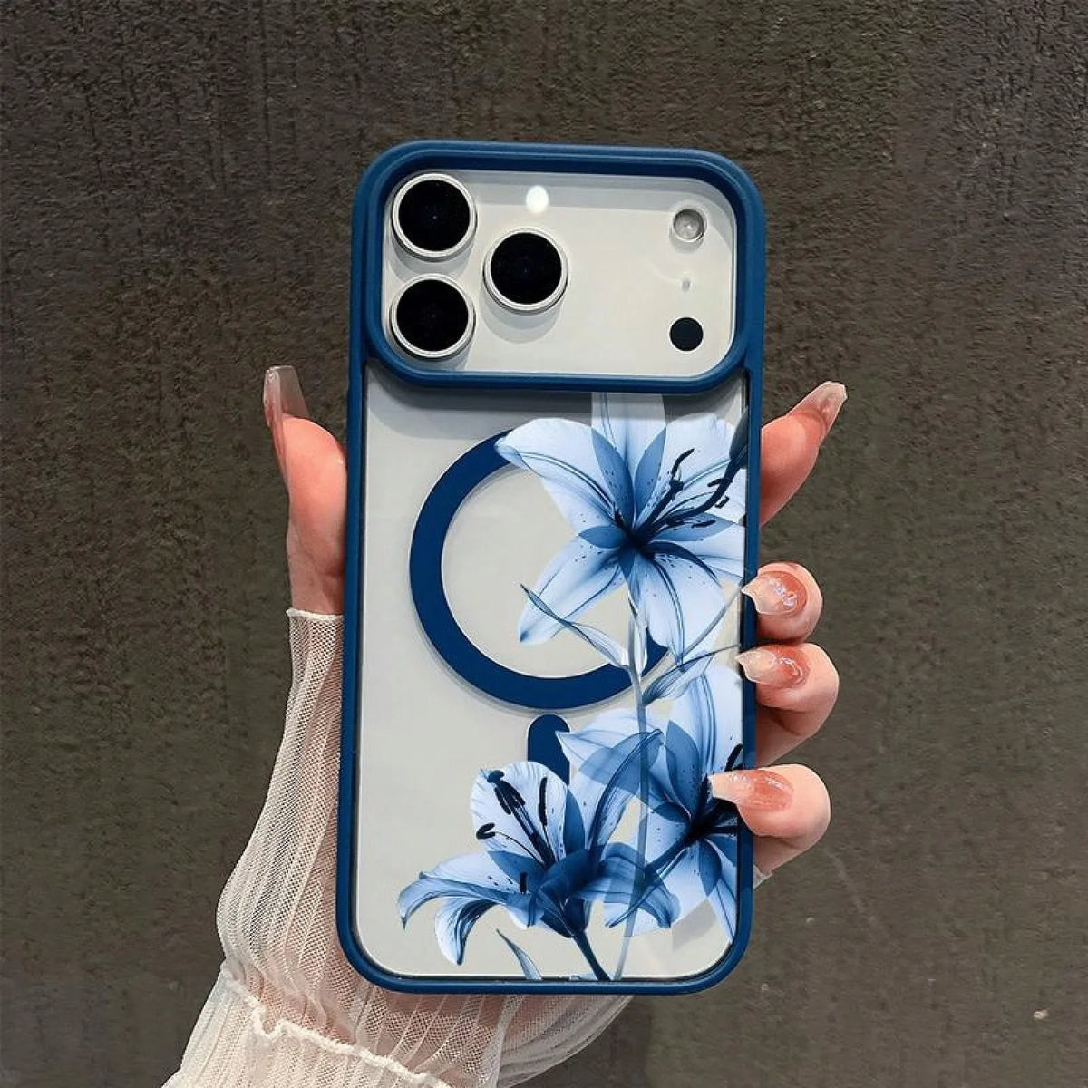 A hand holds a blue and white floral patterned magnetic phone case with a matte clear finish.