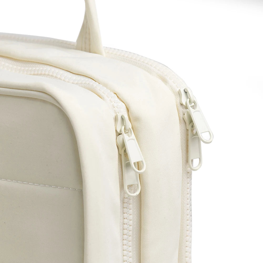 A close-up of a cream-colored portable hanging toiletry bag with a zipper detail.