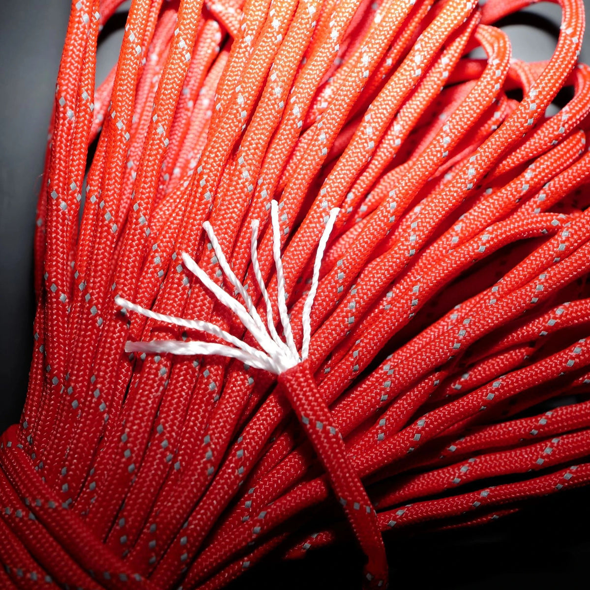 A close-up of bright red reflective paracord rope strands bundled together.