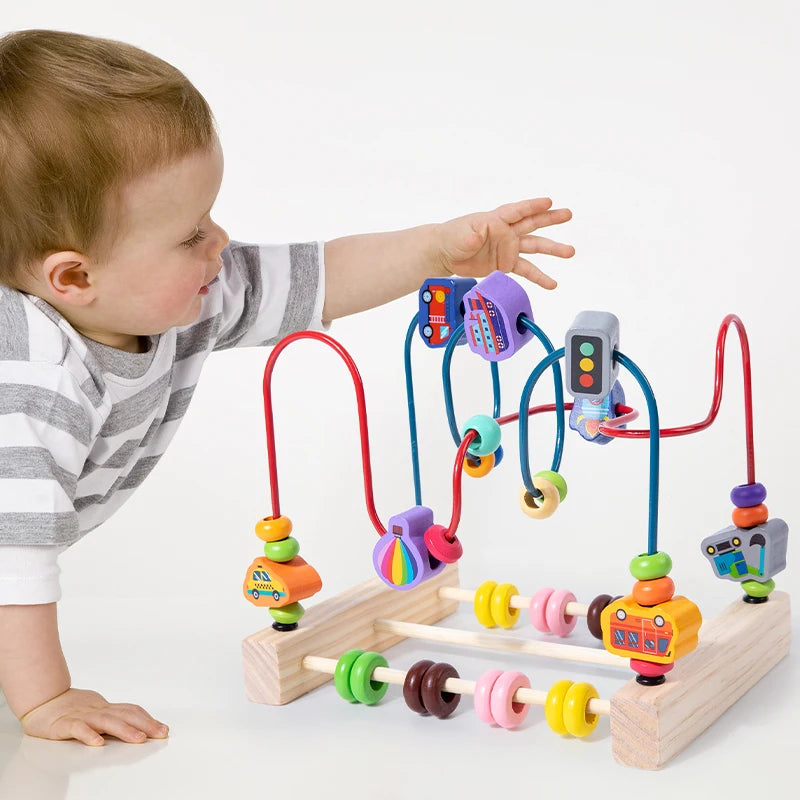 A baby is interacting with a wooden bead maze roller coaster toy featuring colorful beads and an abacus counter.