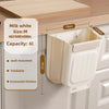 A beige foldable hanging trash bin with a lid is shown mounted on a wooden cabinet shelf.