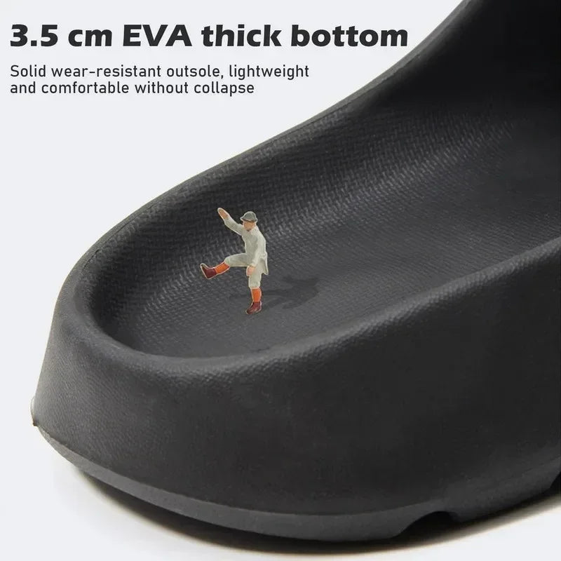 A close-up view of a black EVA slide with a molded foot shape, showing a small figure inside for scale.