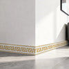 A white wall features a gold geometric border trim along the baseboard.