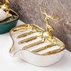Gold leaf-shaped ceramic soap dish with a drain rack on a white surface.