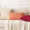 A set of four textured throw pillows in shades of pink, peach, and terracotta resting on a light-colored sofa.
