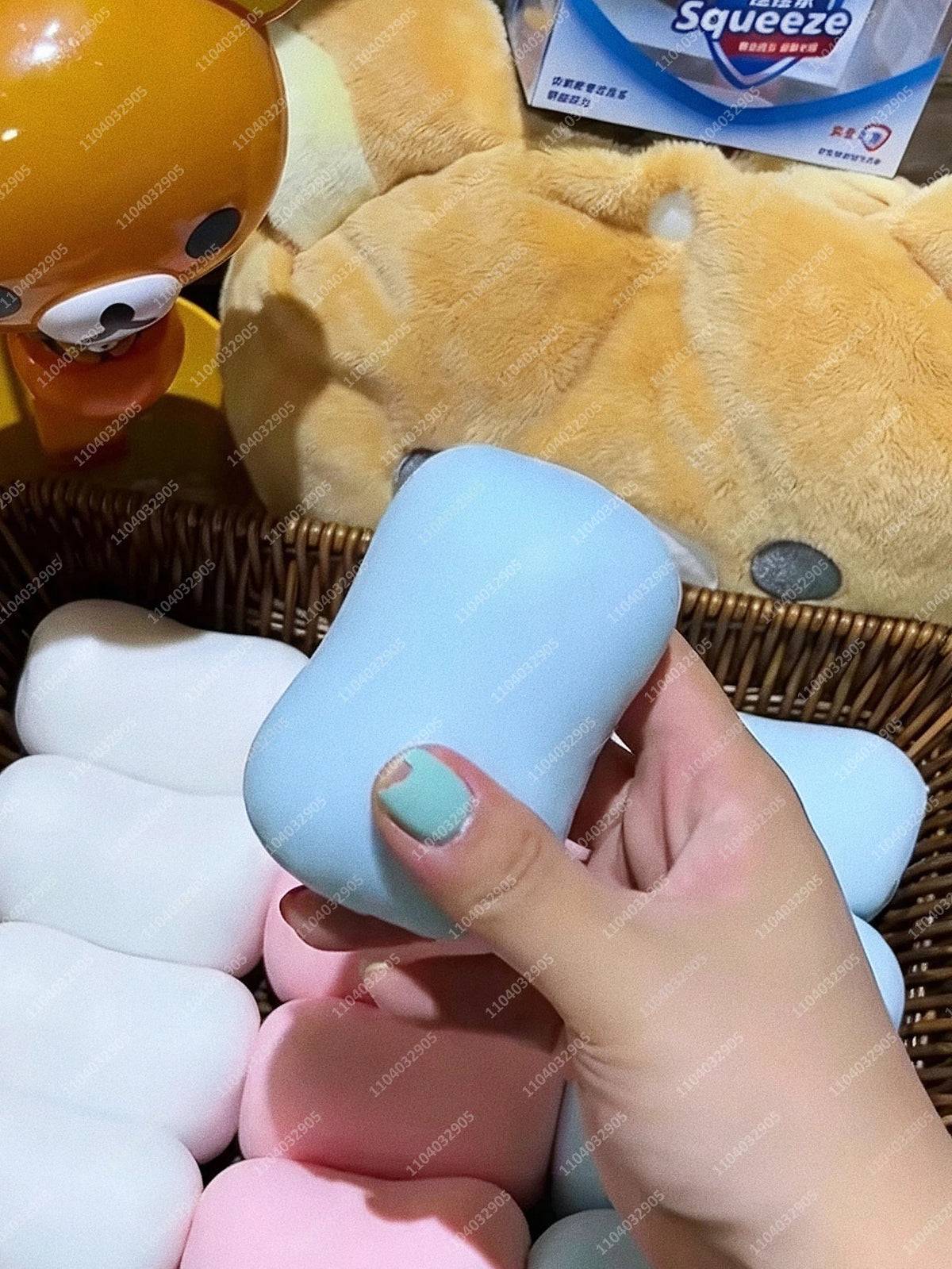 Eine Hand hält einen hellblauen Silikon-Stressball-Fidget-Spielzeug, umgeben von verschiedenen bunten Schaumstoffbällen.