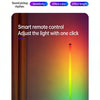 A hand holds a smart remote control for adjusting an RGB LED corner floor lamp.