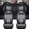 A pair of black full coverage PU leather car seat covers shown in a studio setting.