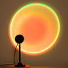 A black lamp projector casts a vibrant, multicolored sunset glow onto a wall.