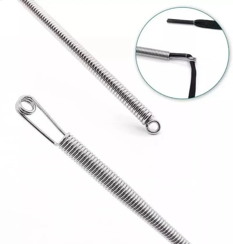 A close-up view of a silver spring drawstring needle threader tool with a long, coiled metal shaft.