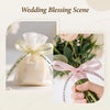 A wedding blessing scene featuring a white satin ribbon tied around a small package and a bouquet of green foliage.
