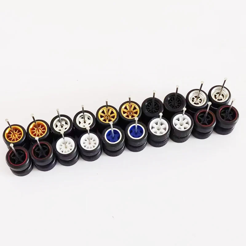A collection of ten pairs of 1:64 scale alloy car wheels and tires in various colors including gold, black, and blue.