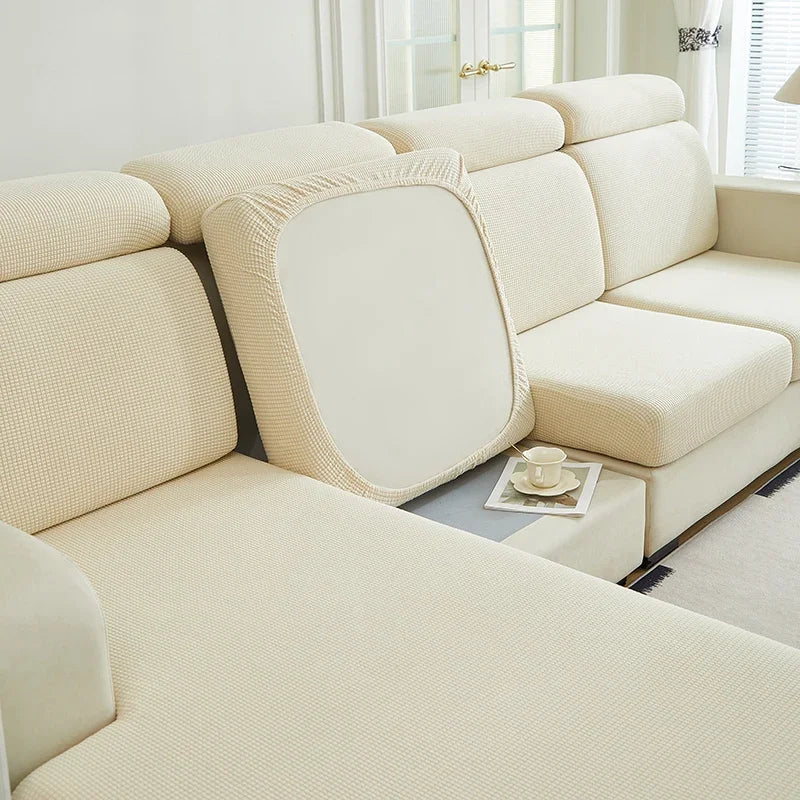 A light beige elegant stretch sofa slipcover with a textured fabric and a removable back cushion.