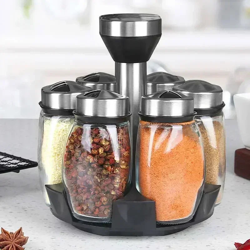 A set of rotating glass spice jars with a black rack for storage and display.