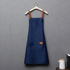Navy blue waterproof adjustable kitchen apron hanging on a wooden hanger