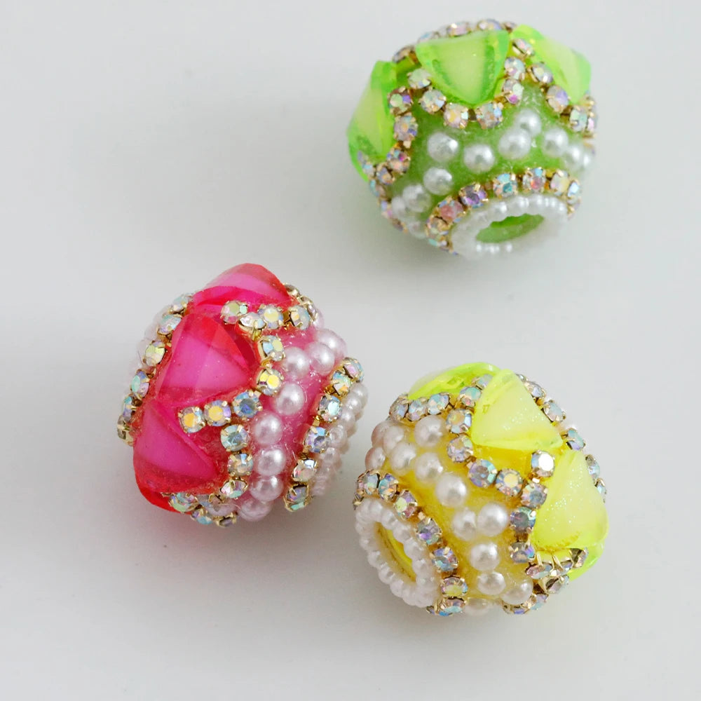 Three spherical beads made of green, pink, and yellow rhinestones and white round beads for jewelry making