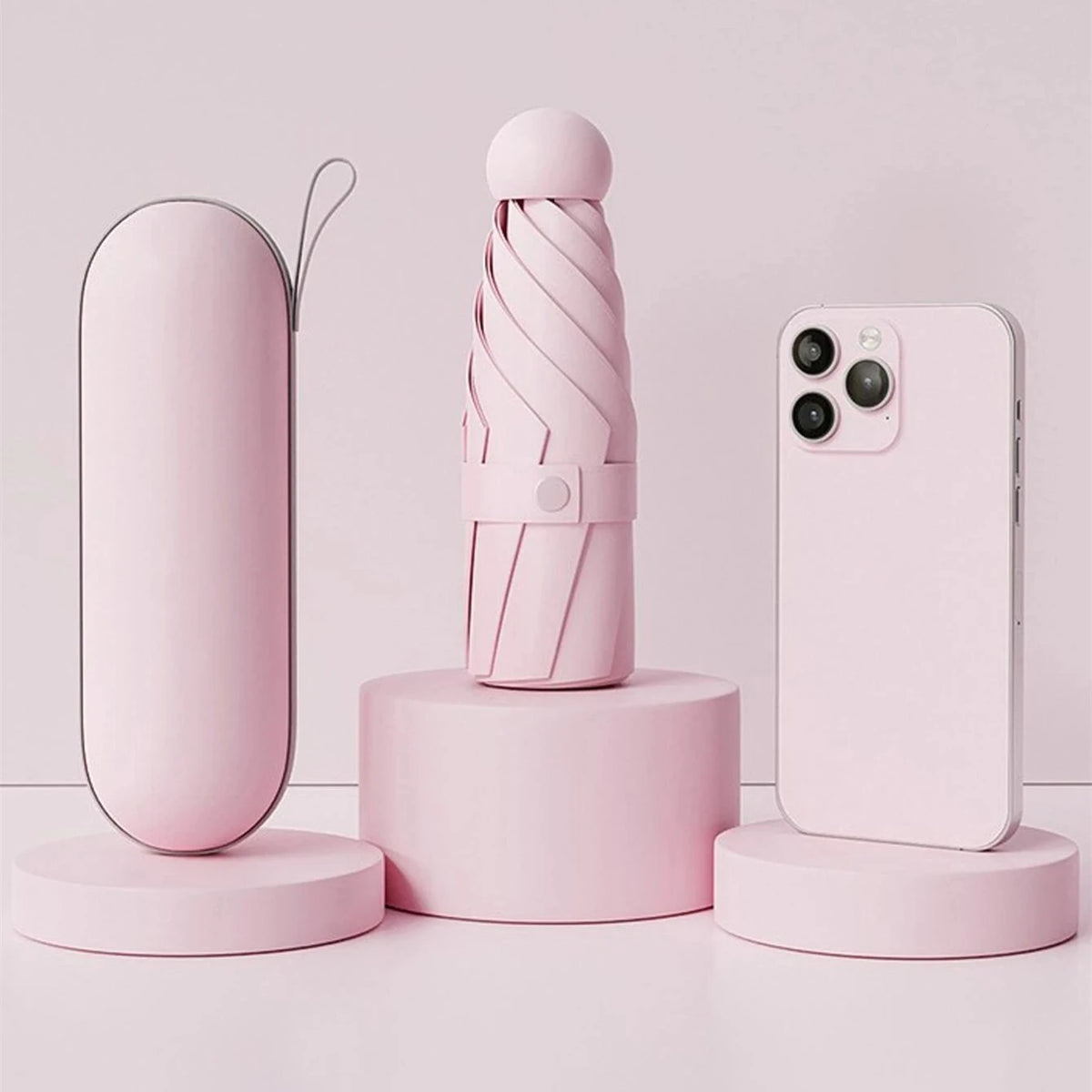 A pink compact folding umbrella is displayed next to a smartphone, set against a light background.