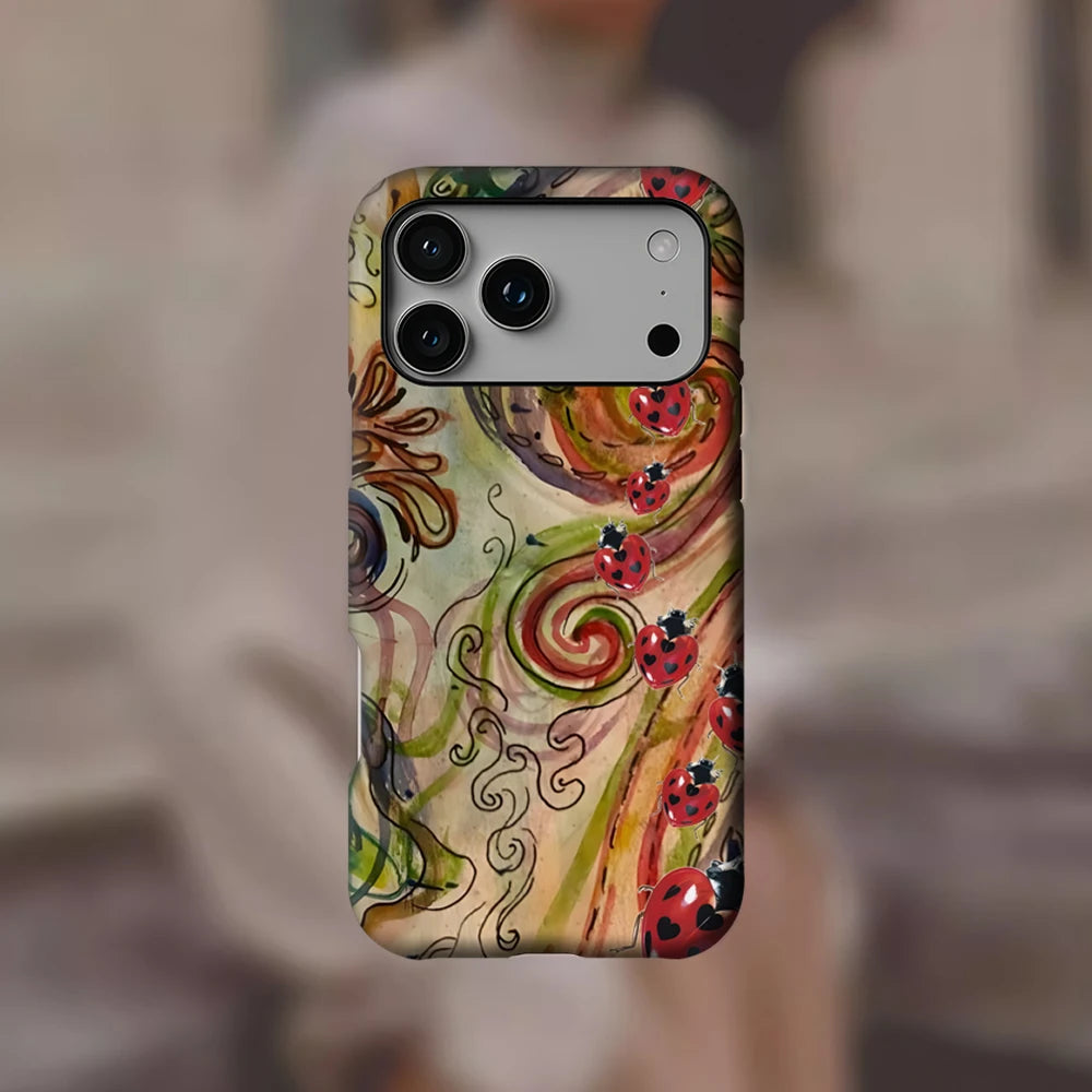 A phone case featuring a swirling pattern of ladybugs and floral designs.