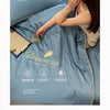 A close-up of a light blue comforter with embroidery, showing a hand touching the fabric.