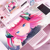 Anime character illustration of a pink-haired girl on a mouse pad next to various desk accessories.