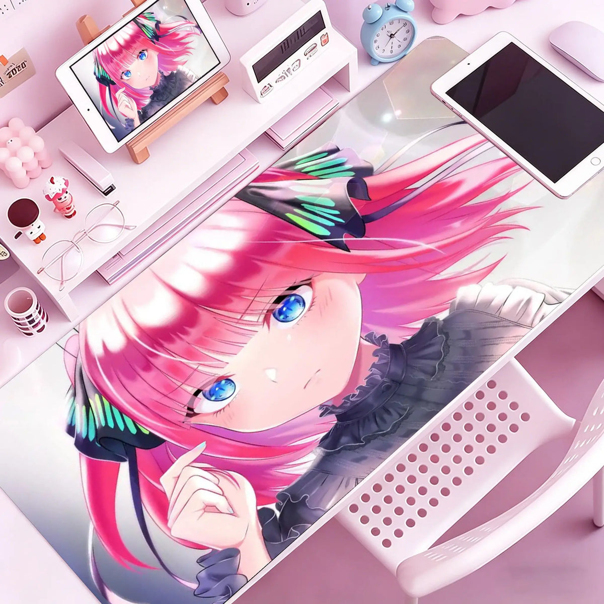 Anime character illustration of a pink-haired girl on a mouse pad next to various desk accessories.