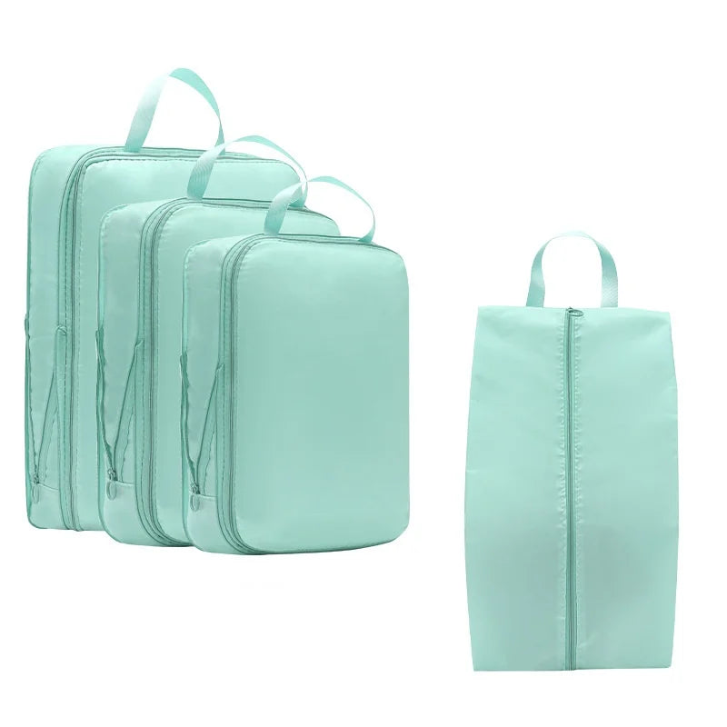A set of light mint green compressible packing cubes for travel organization.